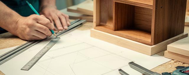 Falegname che annota misure per un mobile su misura accanto a un disegno tecnico